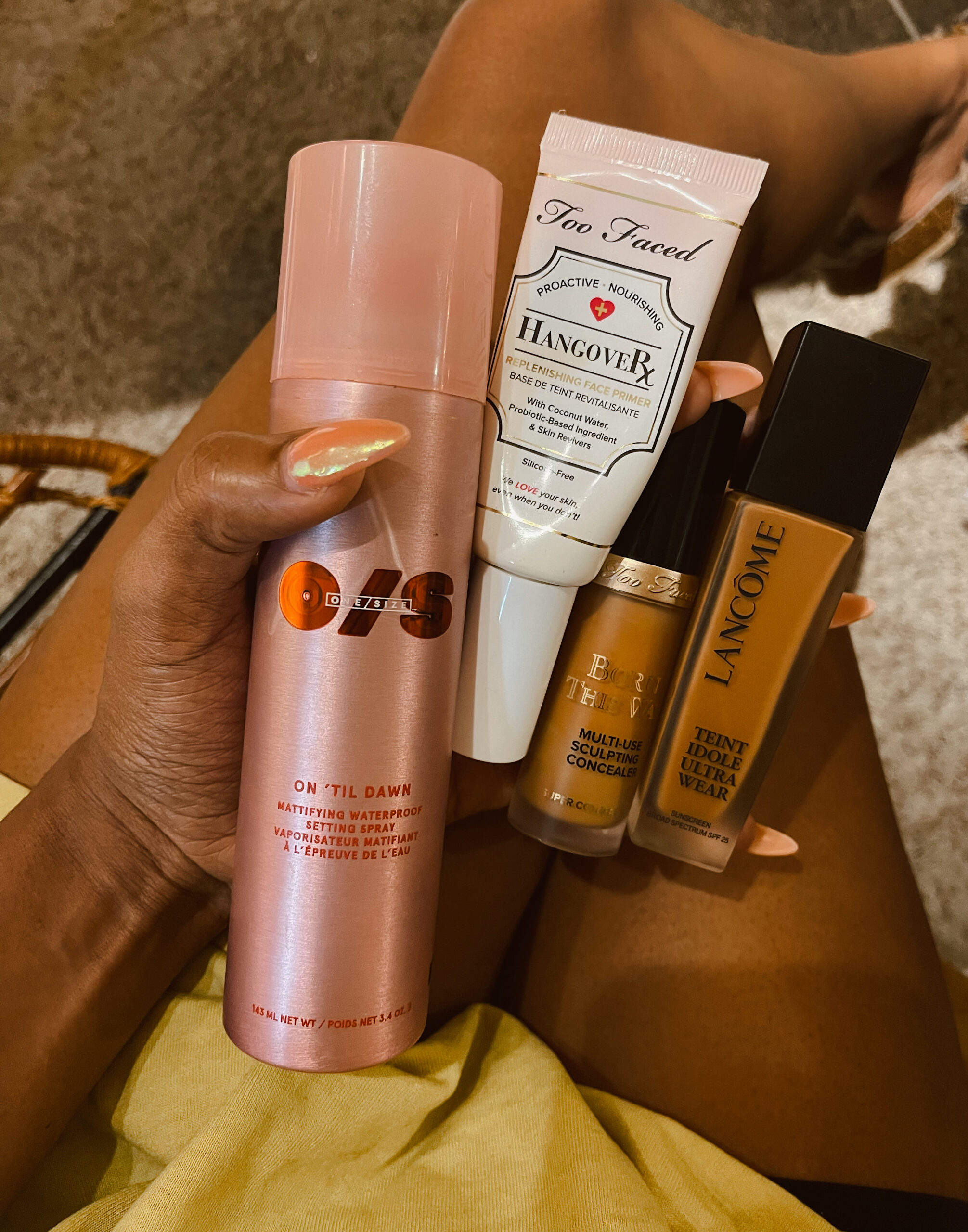 Collection of beauty makeup products including facial mist, setting spray, primer, and foundation arranged for a beauty routine.